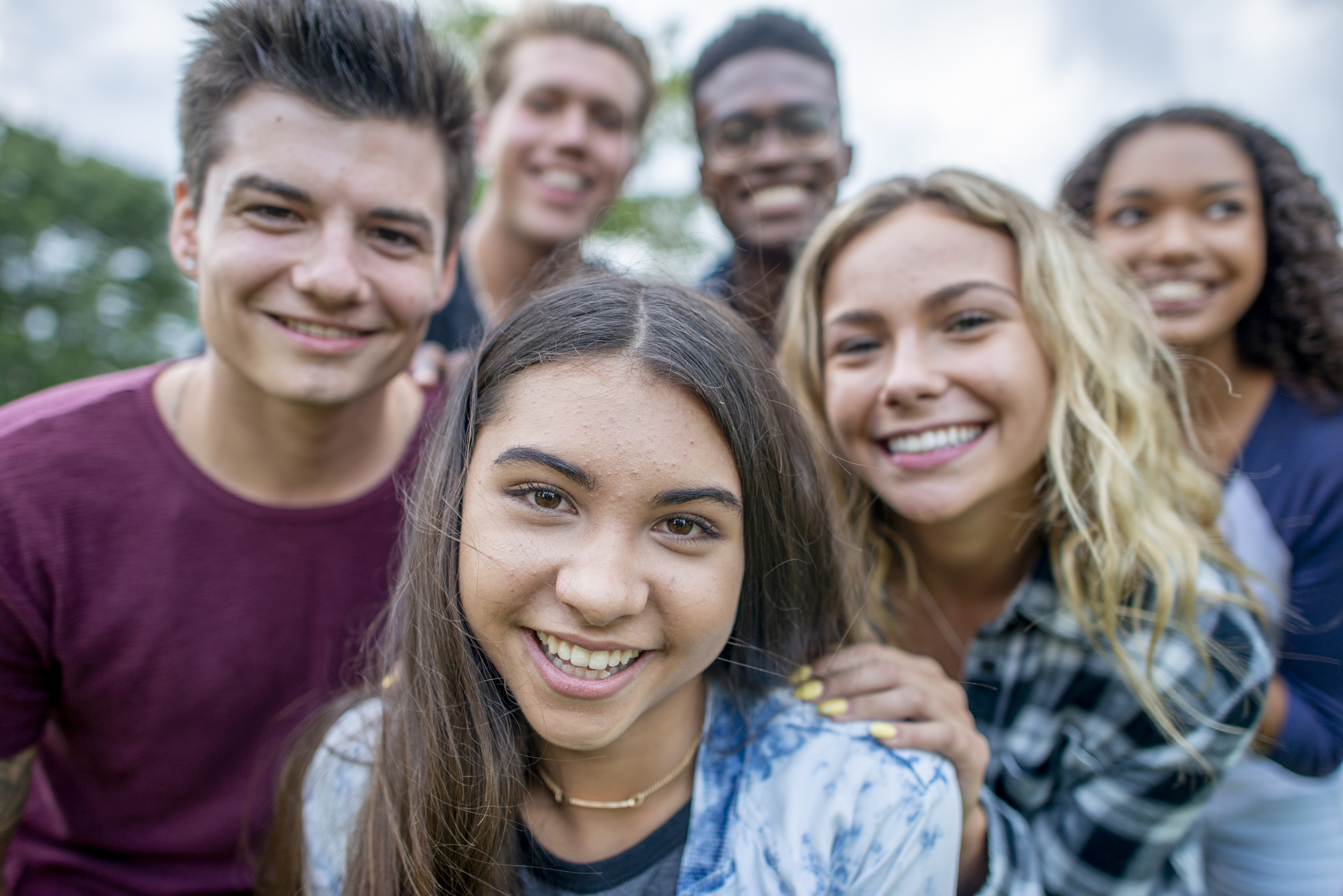 Group of five adolescents of different genders and complexions smiling for a selfie.