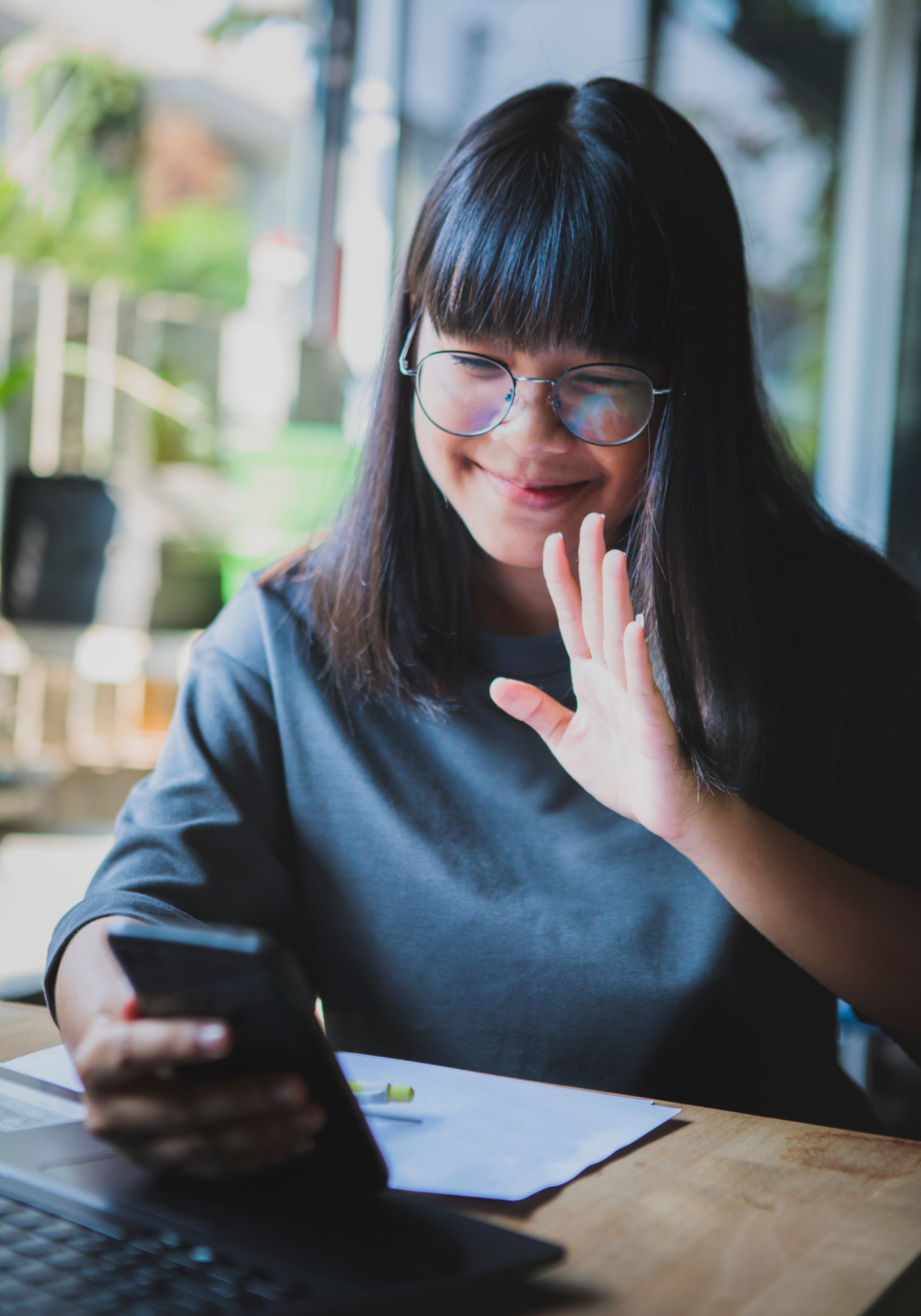 Adolescent waving to a video call on her mobile phone